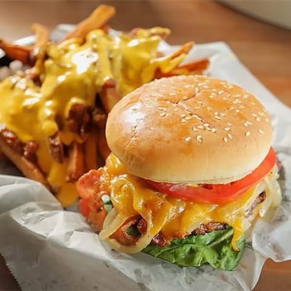 A Borinquen Restaurant burger with cheese, bacon, lettuce, tomato, and onions, served with cheesy fries.