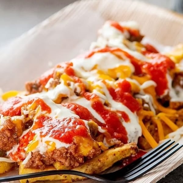 Close-up of loaded Puerto Rican fries with meat, cheese, ketchup, and mayo-ketchup sauce.